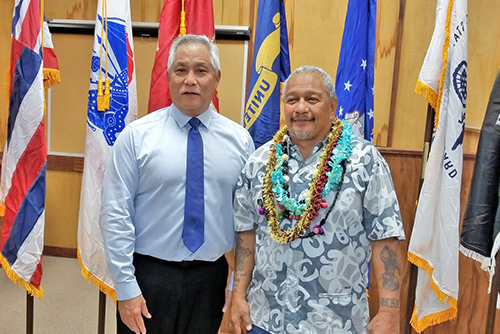 Judge Melvin Fujino standing with Big Island Veterans Treatment Court’s 11th graduate in the Kona courtroom, military flags behind them, 11/05/2018.