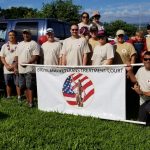 First Circuit Judge Edward Kubo, Jr., and Third Circuit Judge Henry Nakamoto with Veterans Treatment Court associates standing outside on a sunny blue-sky day, on a lawn with a Big Island Veterans Treatment Court banner at the Hilo Veterans Day Parade, 11/09/19.