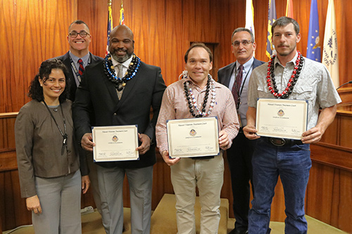 A group of six people, three holding plaques.