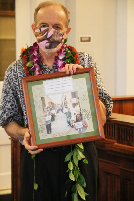 Justice Pollack holds the photo given to him by staff of the Hawaii Supreme Court. In the photo, the justices and staff members are social distancing and wearing masks.