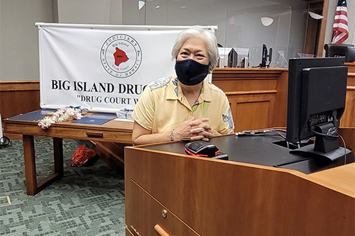 Friends of Big Island Drug Court Board member Debbie Maiava Ching, at a courtroom podium, shares her thoughts with attendees at the Big Island Drug Court’s 57th graduation ceremony, 08/05/2021.