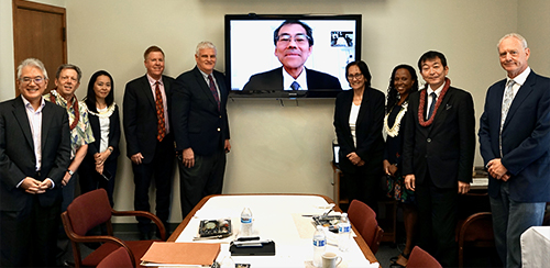 Associates of the University of Hawaii William S. Richardson School of Law, Hawaii State Bar Association International Law Section, and the Hawaii Supreme Court stand to the left and right of a large video screen transmitting a live-feed from Japan of Associate Justice Katsuya Uga of the Supreme Court of Japan, 05-03-2022.