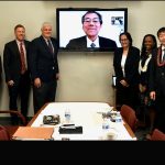 Associates of the University of Hawaii William S. Richardson School of Law, Hawaii State Bar Association International Law Section, and the Hawaii Supreme Court stand to the left and right of a large video screen transmitting a live-feed from Japan of Associate Justice Katsuya Uga of the Supreme Court of Japan, 05-03-2022.