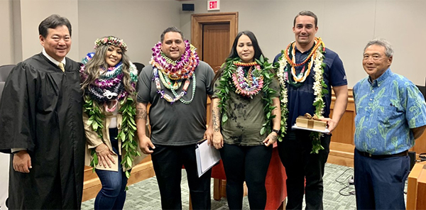Hilo Drug Court Judge Peter Kubota, four graduates, and Third Circuit Chief Judge Greg Nakamura (Retired) in the Hilo courtroom, 05/12/2022.