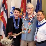 Big Island Veterans Treatment Court Judge Wendy DeWeese, David Riehle, and Chief Judge Robert Kim stand in front of the U.S., State of Hawaii, and military branch flags at the Kona courthouse, July 11, 2022.