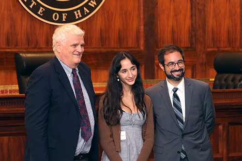 Hawaii Supreme Court Chief Justice Mark E. Recktenwald, Seabury Hall student Barbara Goldyn, and attorney Jacob K. Lowenthal stand together in front of the Hawaii Supreme Court bench at the Pro Bono Celebration, 10/27/2022.
