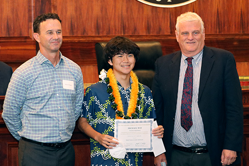 Attorney Blaine Rogers of the Davis Levin Livingston law firm, Punahou School student Michael May, and Chief Justice Mark E. Recktenwald stand together in front of the Hawaii Supreme Court bench at the Pro Bono Celebration, 10/27/2022.
