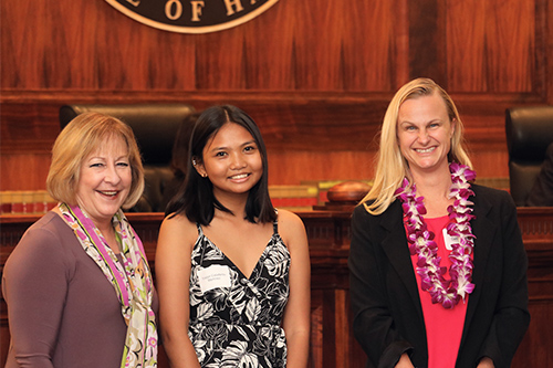 Department of Education Deputy Superintendent Heidi Armstrong, Waimea High School student Trislyn Calixterio-Martinez, and attorney Caitlin Moon stand together in front of the Hawaii Supreme Court bench at the Pro Bono Celebration, 10/27/2022.