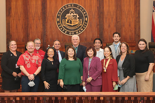Attorneys and Judiciary staff who provided support for the Kapolei Access to Justice Room stand togther at the front of the Hawaii Supreme Court courtroom, 12/16/2022.