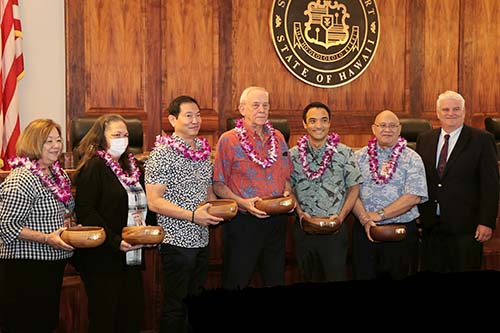 Standing in front of the bench of the Hawaii Supreme Court courtroom, holding their Spirit of Justice Award monkeypod bowls, from left: Legislative Coordinating/Special Projects Office Special Projects Coordinator Karen Takahashi, Legislative Coordinating/Special Projects Office Legislative Office Assistant Lori Rutherford, Budget Administrator & Deputy Department Head Gary Teramae, Policy & Planning Department Head Tom Mick, Deputy Administrative Director of the Courts Brandon Kimura, Administrative Director of the Courts Rodney Maile, and Chief Justice Mark Recktenwald, 10/25/2023.