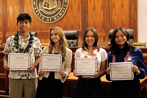 Rafael Firme (Campbell High School), Arianna Rector (Haleakalā Waldorf School), Satomi Lakin (ʻIolani School), and Maiyah Panis-Vuong (Waiākea High School) in front of the Hawaiʻi Supreme Court courtroom bench holding their award certificates at the Hawaiʻi Access to Justice Commission's 2023 Pro Bono Celebration, 10/26/2023.