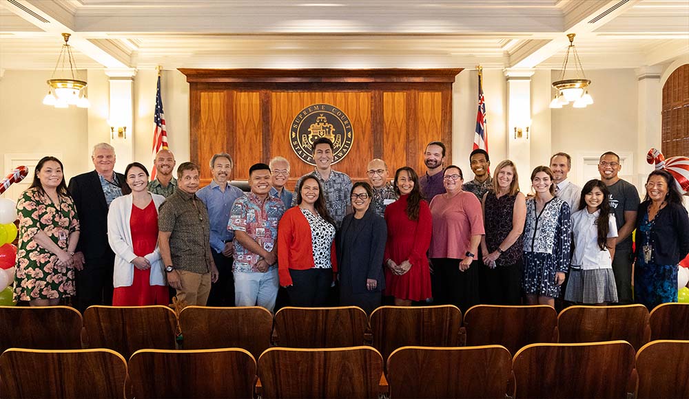 Attorneys and Judiciary staff who provided support for the Honolulu District Court Access to Justice Room stand together at the front of the Hawaii Supreme Court courtroom, 12/12/2023.