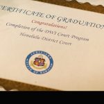 Picture of a certificate of graduation from the Honolulu DWI Court Program, with blue and white lei placed over the top left corner.