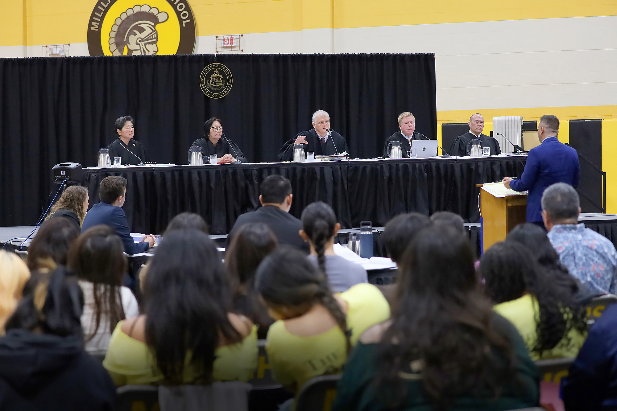 Image of the Hawaiʻi Supreme Court listens to oral argument at Mililani High School. From left, Justice Lisa Ginoza, Justice Sabrina McKenna, Chief Justice Mark Recktenwald, Justice Todd Eddins, and Justice Vladimir Devens.