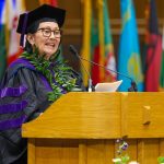 Hawaiʻi Supreme Court Associate Justice Sabrina McKenna wears a purple and black graduation cap and gown while standing behind a podium on a stage at Cameron Indoor Stadium on the Duke University campus during her speech to fellow graduates and others gathered for Duke Law’s convocation ceremony on May 10, 2025.