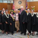 New Circuit Judge Kauanoe A.D. Jackson poses for a photograph with Hawaii Governor Josh Green, Hawaii Supreme Court Chief Justice Mark Recktenwald and nine other judges from Hawaii Island after Jackson’s swearing-in ceremony at the Keahuolū Courthouse in Kailua-Kona on June 2, 2025. The judges are all wearing black robes. Governor Green is wearing a sport coat over a pink shirt. Everyone is wearing at least one lei.