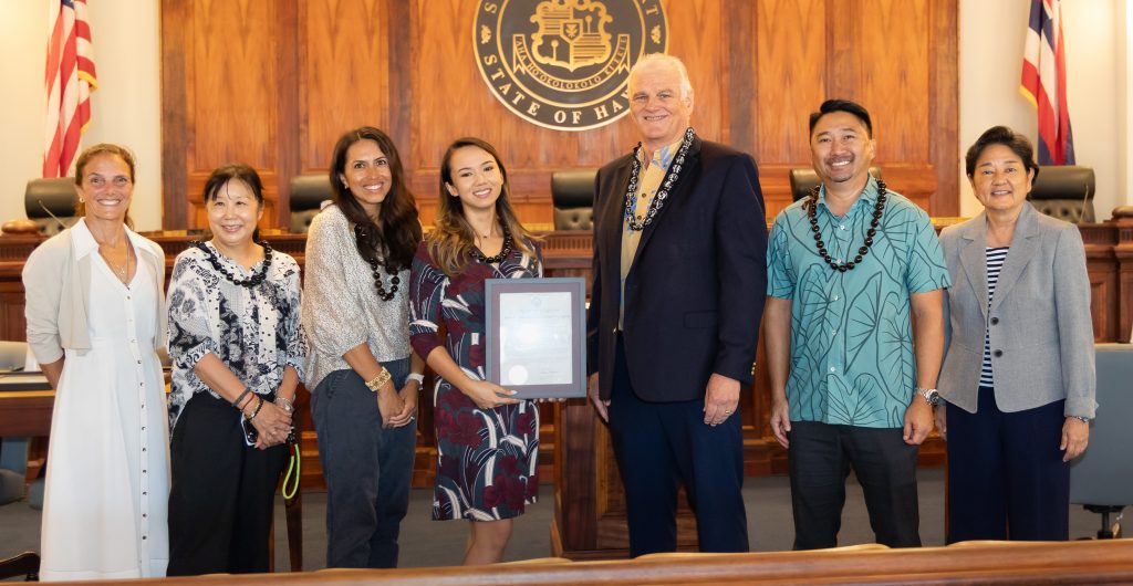 Chief Justice Mark Recktenwald poses with State Representative Amy Perruso, Justice Lisa Ginoza, Anthology FINN and four employees from the Anthology FINN Partners marketing and communications firm in the Supreme Court courthouse. Anthology employee Shannon Manamtam is holding the certificate of appreciation Chief Justice Recktenwald presented to Anthology minutes earlier.