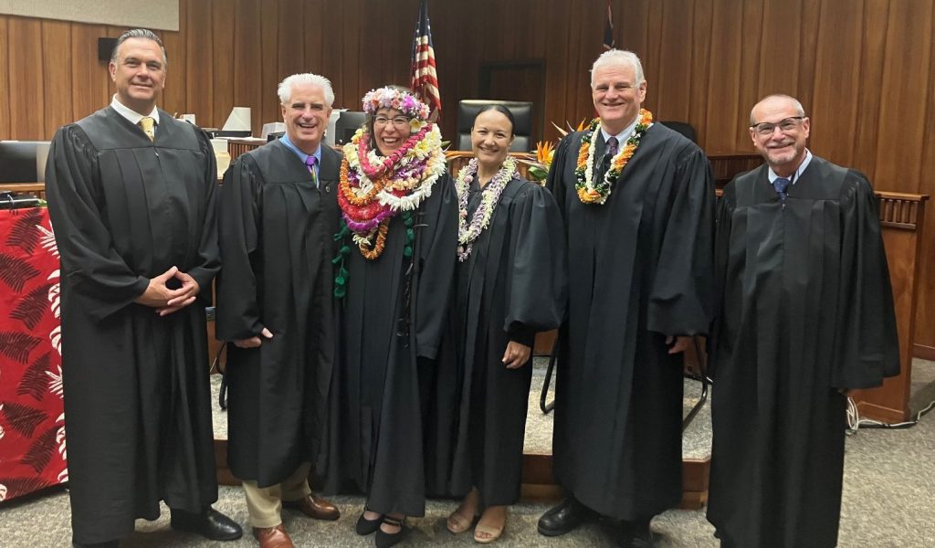 Judge Sonya Toma is adorned in several lei as she poses for a photograph in a courtroom with Chief Justice Mark Recktenwald and fellow Maui judges after taking the oath of office at the Hoapili Hale in Wailuku.