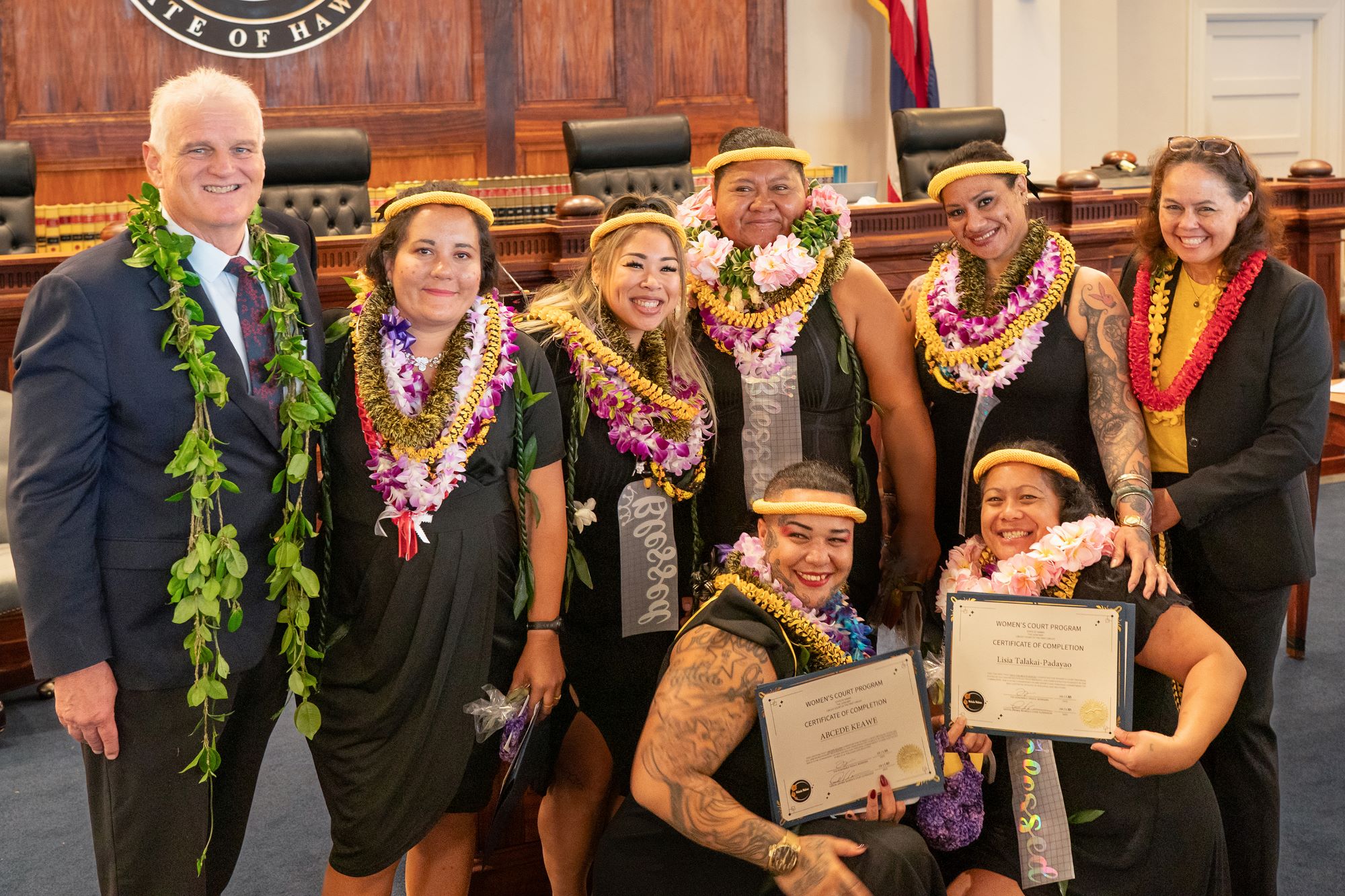 The six women graduates honored during the first-ever commencement ceremony for the Mohala Wahine program, or Women’s Court, pose for a photograph with Chief Justice Mark Recktenwald and Circuit Court Judge Trish Morikawa, who oversees Women’s Court, in the Hawaiʻi Supreme Court courtroom.