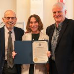 Family law attorney William C. Darrah and The Mediation Center of the Pacific’s Executive Director Tracey S. Wiltgen (holding up a copy of the chief justice’s proclamation), and Hawaiʻi Supreme Court Chief Justice Mark E. Recktenwald, in the Hawaiʻi Supreme Court courtroom for a presentation commemorating the 300th Seminar of Divorce Law in Hawaiʻi, 07-16-2025.