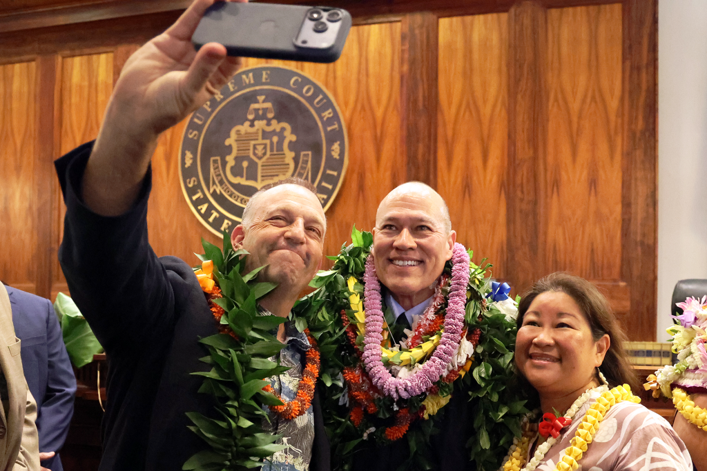 Hawai'i Governor Josh Green (left) takes a photo with Chief Justice Vladimir P. Devens and First Lady Jamie Green (right).