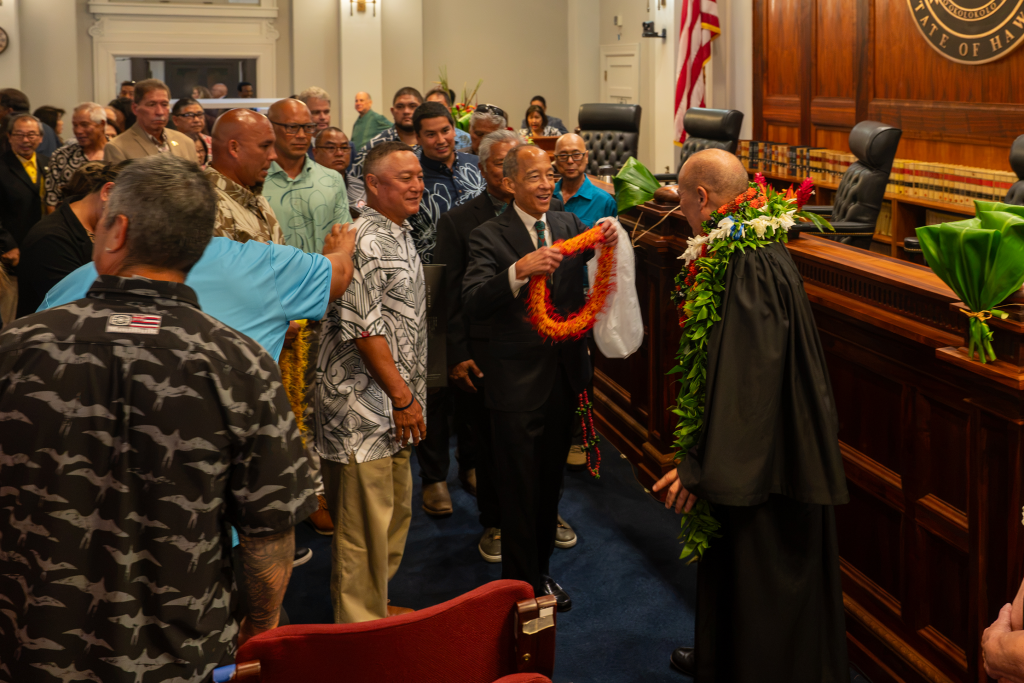 Hawaiʻi State Bar Association President Mark Murakami presents Chief Justice Vladimir P. Devens with a lei following his investiture ceremony on August 3 at Aliʻiōlani Hale, as dozens of friends, family, and colleagues wait in line to greet and lei the new Chief Justice.
